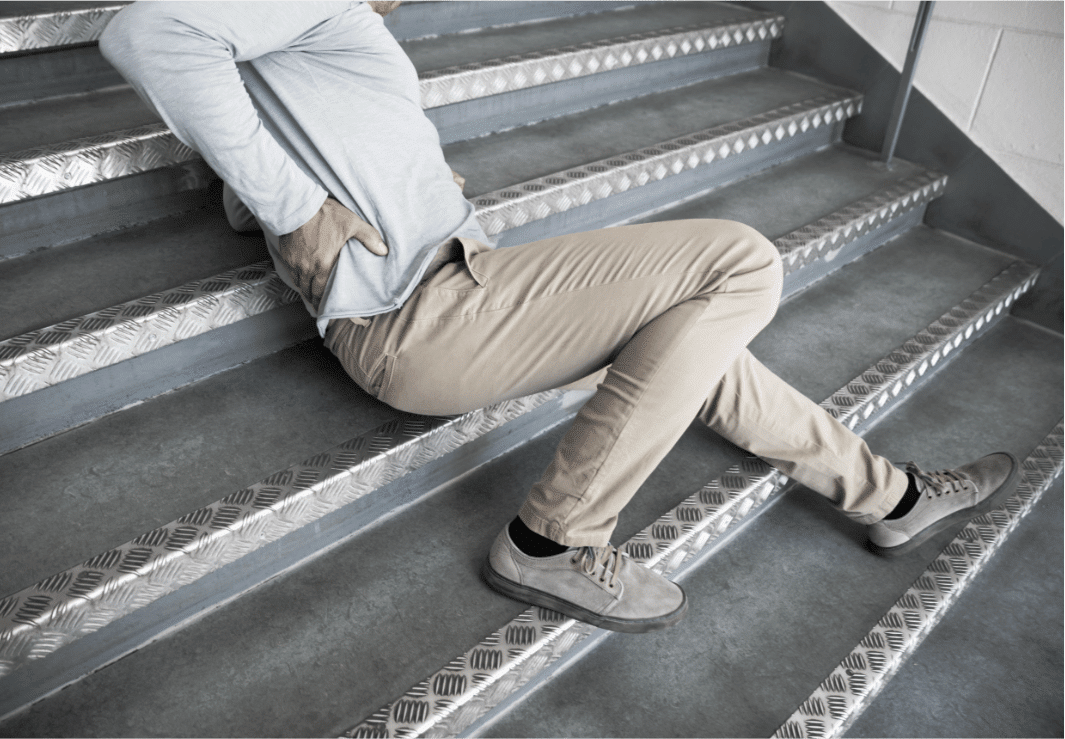 man holding his back while sitting on a stairs