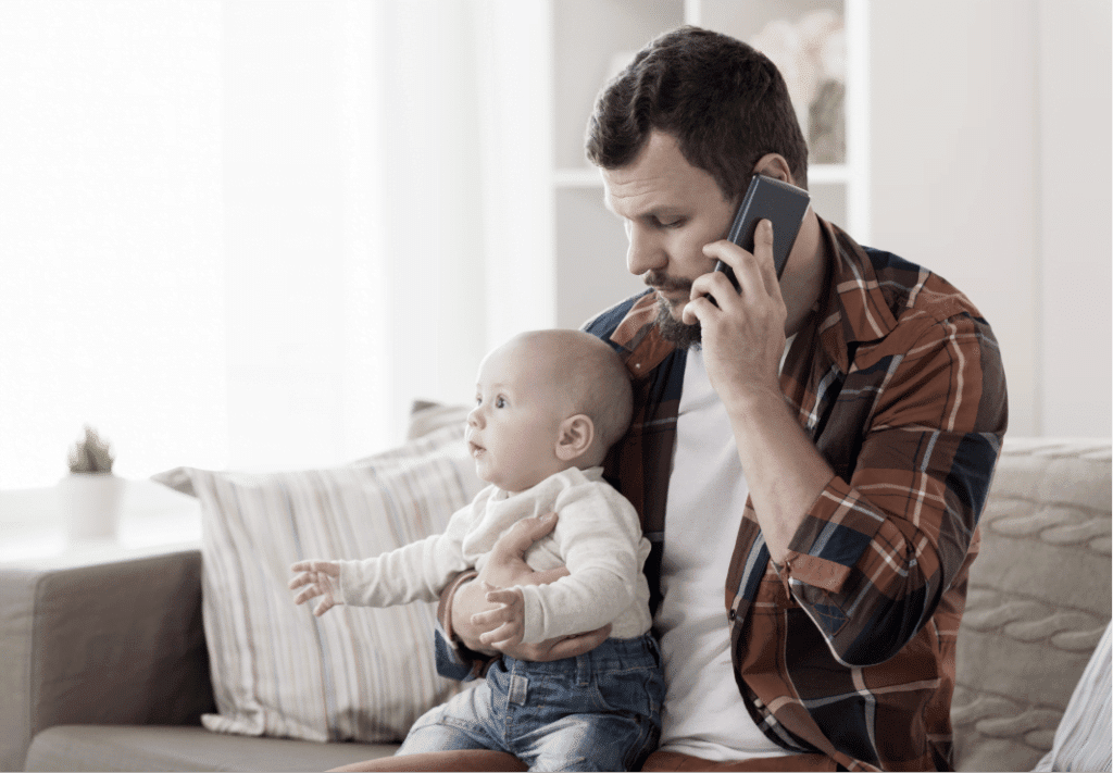 man holding a baby while talking on the phone