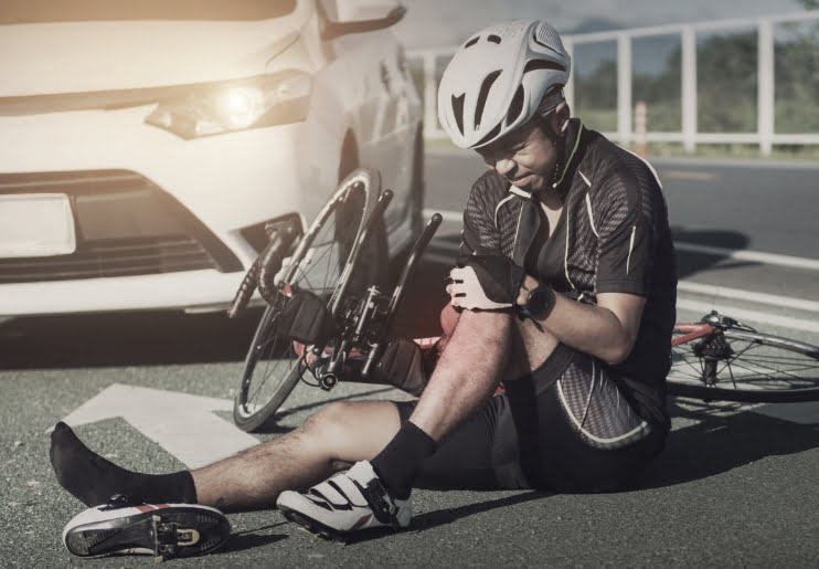 man holding knees on a bicycle accident