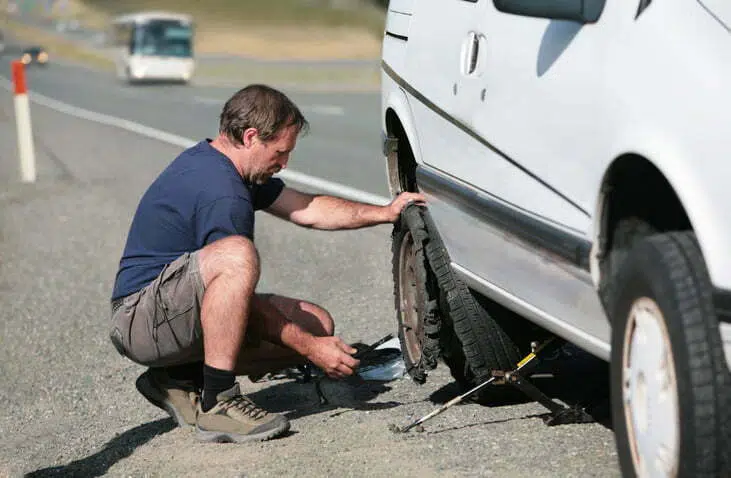 Man changes Flat Tire by the Highway