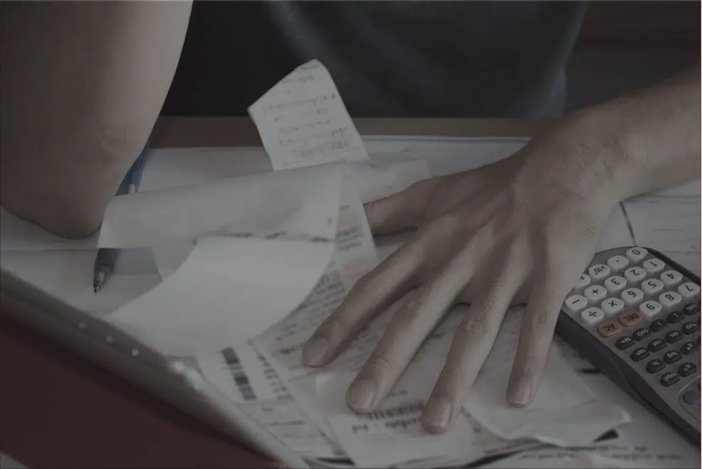 hand above paper bills and calculator