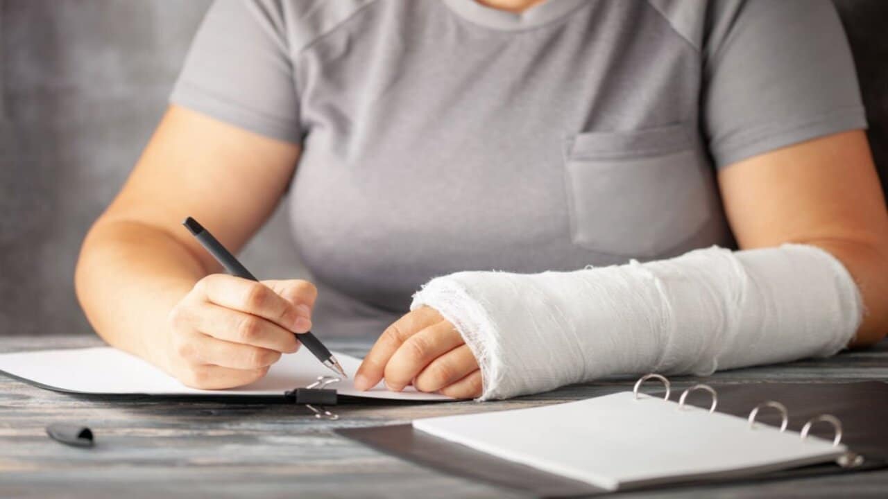 A Woman with a Cast on Her Arm Writes Insurance with a Pen on Paper