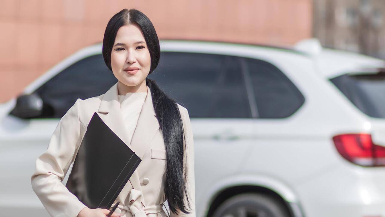 a woman in front of a car for automobile insurance