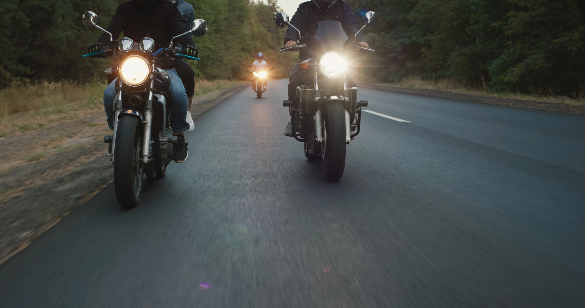 A group of motorcycles traveling down a country highway at dusk; rear end collisions can happen anywhere and at any time.